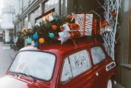 Red retro car with a Christmas tree fir tied to the roof.の写真素材