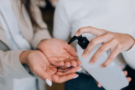 Female hands applying antibacterial liquid soap close up.の写真素材