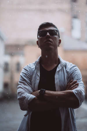Portrait of carefree handsome young man is feeling free under the rain