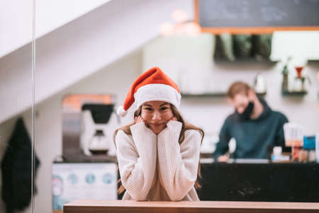 Girl wearing Santa Claus hat sitting in coffee shopの写真素材