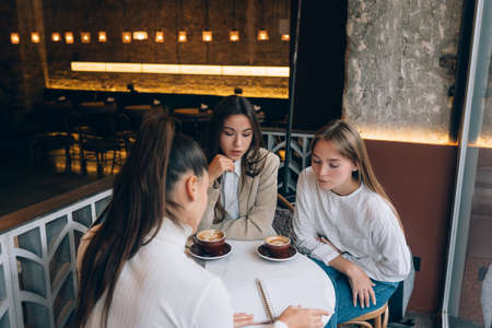 A group of women friends in a cafe working on a projectの写真素材