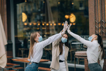 Friends in protective masks give a high five.の写真素材