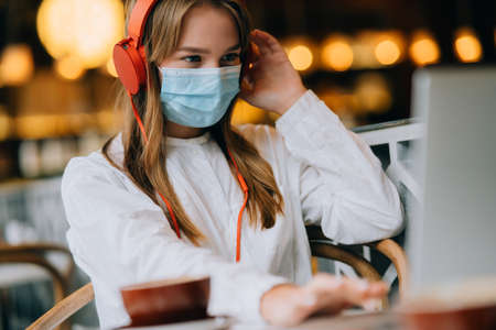 A girl sitting in a coffee shop with headphones.の写真素材