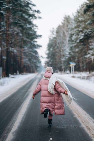 Portrait of a beautiful caucasian woman on a road through snowy forestの写真素材