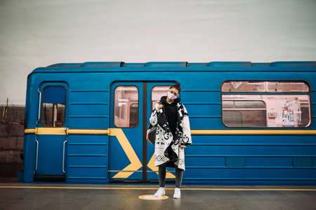 Young woman standing at station in medical protective mask