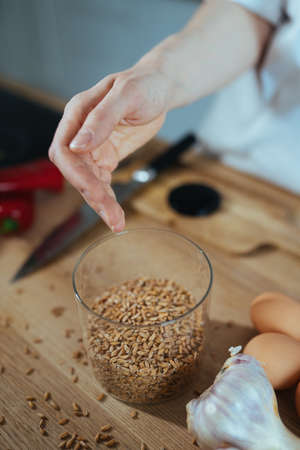 Male hand taking pieces grains in a glass.の写真素材