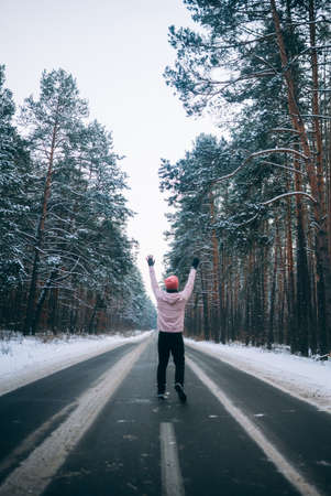 Guy standing on the road in the middle of the forest, surrounded by snowの写真素材