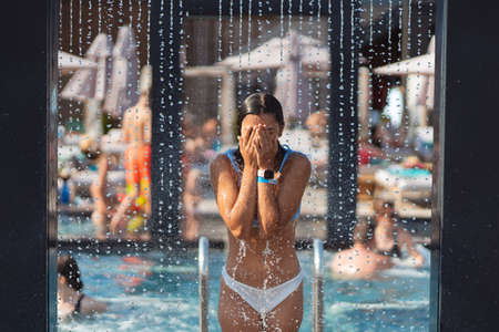 Beautiful Girl In Swimwear Showering Under Water At Resort Beach.