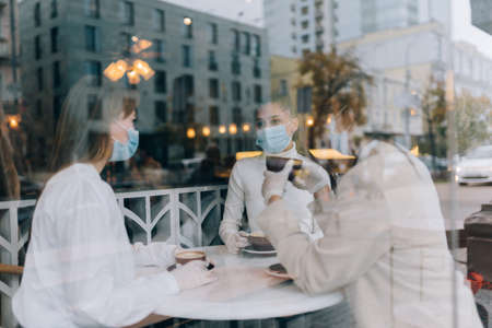 Friends girls met in a cafe. Wear medical protective masks.の写真素材