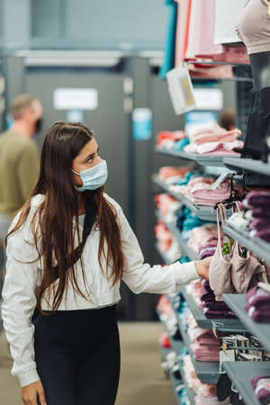 Girl shopper in store wearing medical mask ,choosing underwea