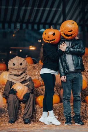 A guy and a girl with a pumpkin heads posing at the scarecrowの写真素材