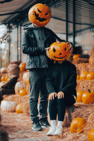 A guy and a girl with a pumpkin heads posing on the streetの写真素材