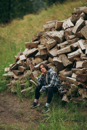 Woman in the forest near the pole of chopped woodの写真素材