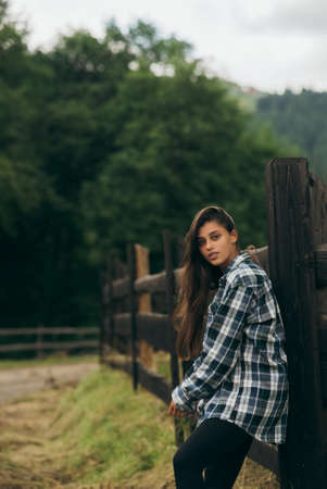 A young attractive Caucasian female stand by a fenceの写真素材
