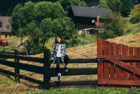 A young attractive Caucasian female sitting on a fence