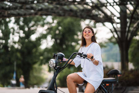 Young beautiful woman and an electric scooter, ecological transportの写真素材