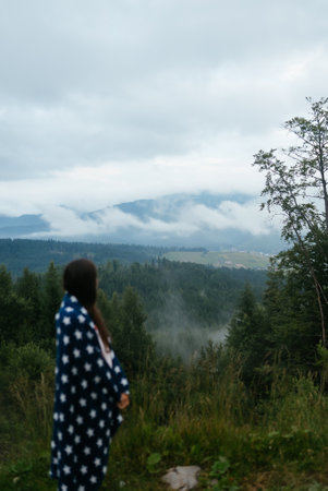 Woman standing on top of a hill, against the background of a valleyの写真素材