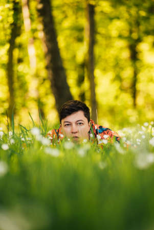 Young man hiding in the green grassの写真素材