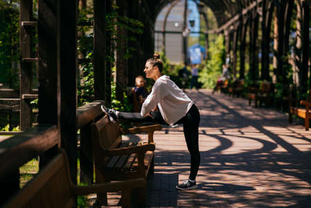 Beautiful young woman goes in for sports in a summer park.