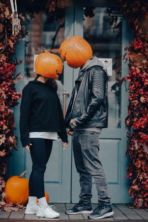 Couple with pumpkin heads posing on camu at the buildingの写真素材