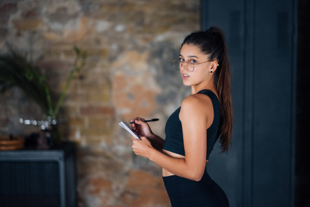 Young women standing writing down something into the notebook.の写真素材