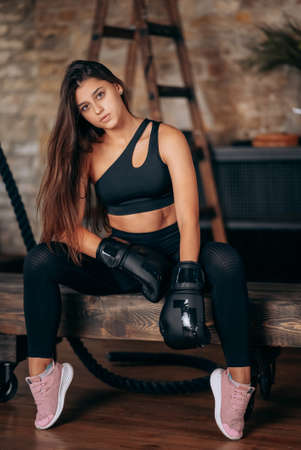 Beautiful young fitness girl posing at camera in black boxing glove