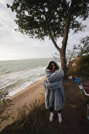 Young woman on cold autumn seashore posing at cameraの写真素材