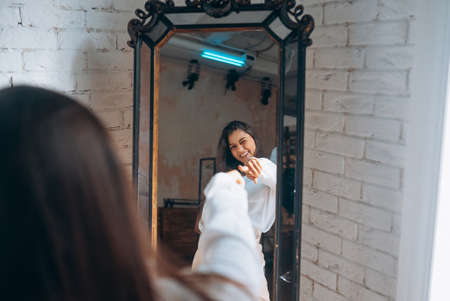 Young woman looks in the mirror. Reflection of a beautiful womanの写真素材