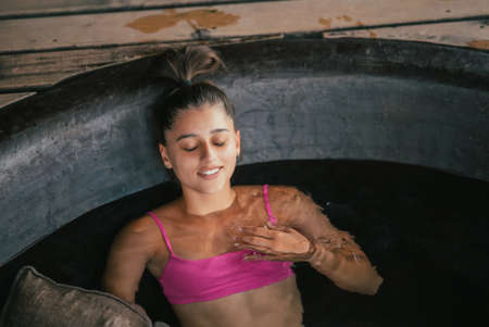 Woman relaxing in round outdoor bath. Organic skin care in hot bath