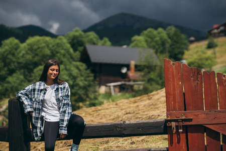 A young attractive Caucasian female sitting on a fenceの写真素材