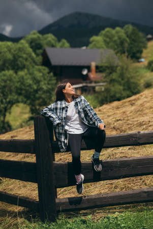 A young attractive Caucasian female sitting on a fenceの写真素材
