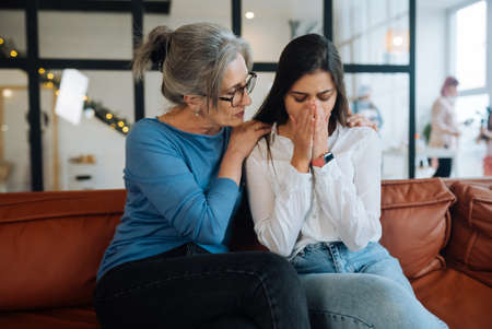 Grandmother comforting her sad granddaughter at home.の写真素材