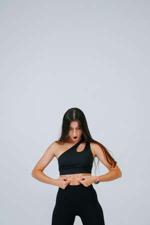 Young woman showing fat on her belly over white background.の写真素材