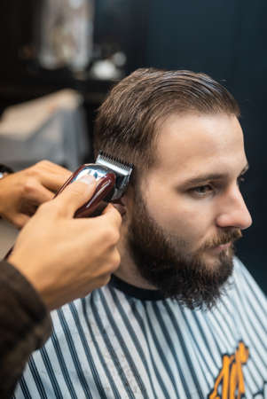 Master in barbershop makes mens haircutting with hair clipperの写真素材