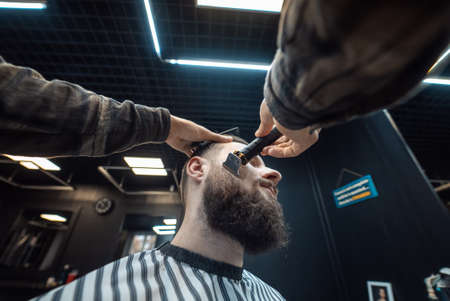 Barber works with a beard clipper. Hipster client getting haircut.の写真素材