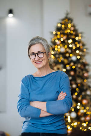 Elderly lady smiling and looking in camera, Xmas tree on backgroundの写真素材