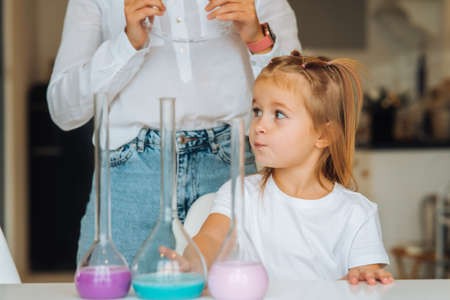 Young woman and little girl mix flasks indoors
