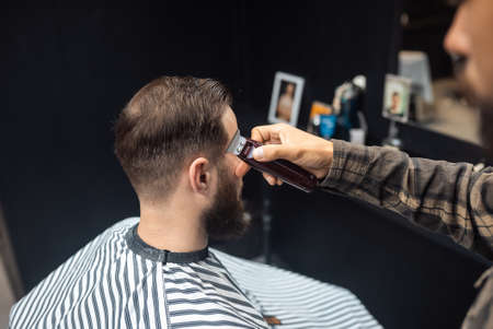 Master in barbershop makes mens haircutting with hair clipperの写真素材