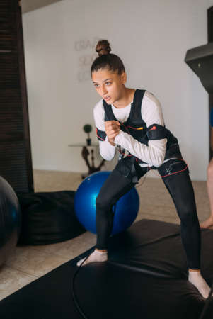 EMS training. Girl doing exercises in a suit with cables.