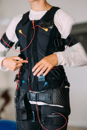 EMS training. Girl doing exercises in a suit with cables.の写真素材