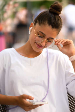 beautiful young woman sitting in street cafe listening to music