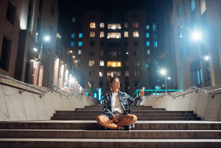 Woman talking via video call in the night cityの写真素材