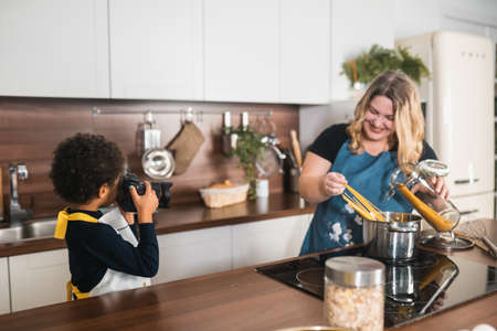 Little girl takes a picture of mom in the kitchen
