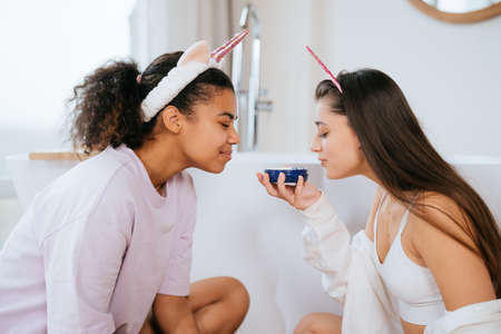Two girls in the bath playing with face creamの写真素材
