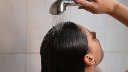Woman taking a long hot shower washing her hair in bathroomの写真素材