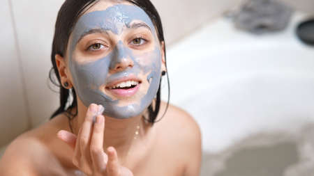 Skin care. Young woman applying clay green mask on her face.の写真素材