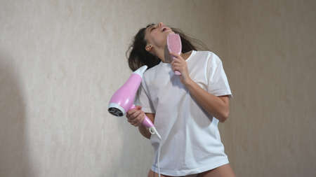 Female drying her hair with hair-drier, flying hair