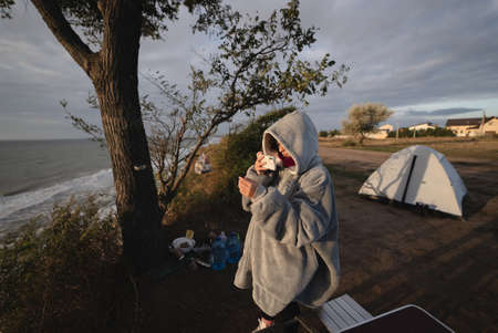 Young woman takes pictures of the sea sunset by smartphoneの写真素材