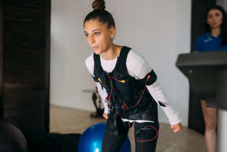 EMS training. Girl doing exercises in a suit with cables.の写真素材