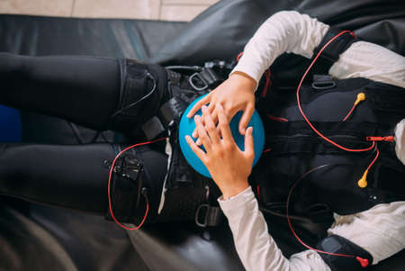 EMS training. The girl lies in a suit with cables.の写真素材